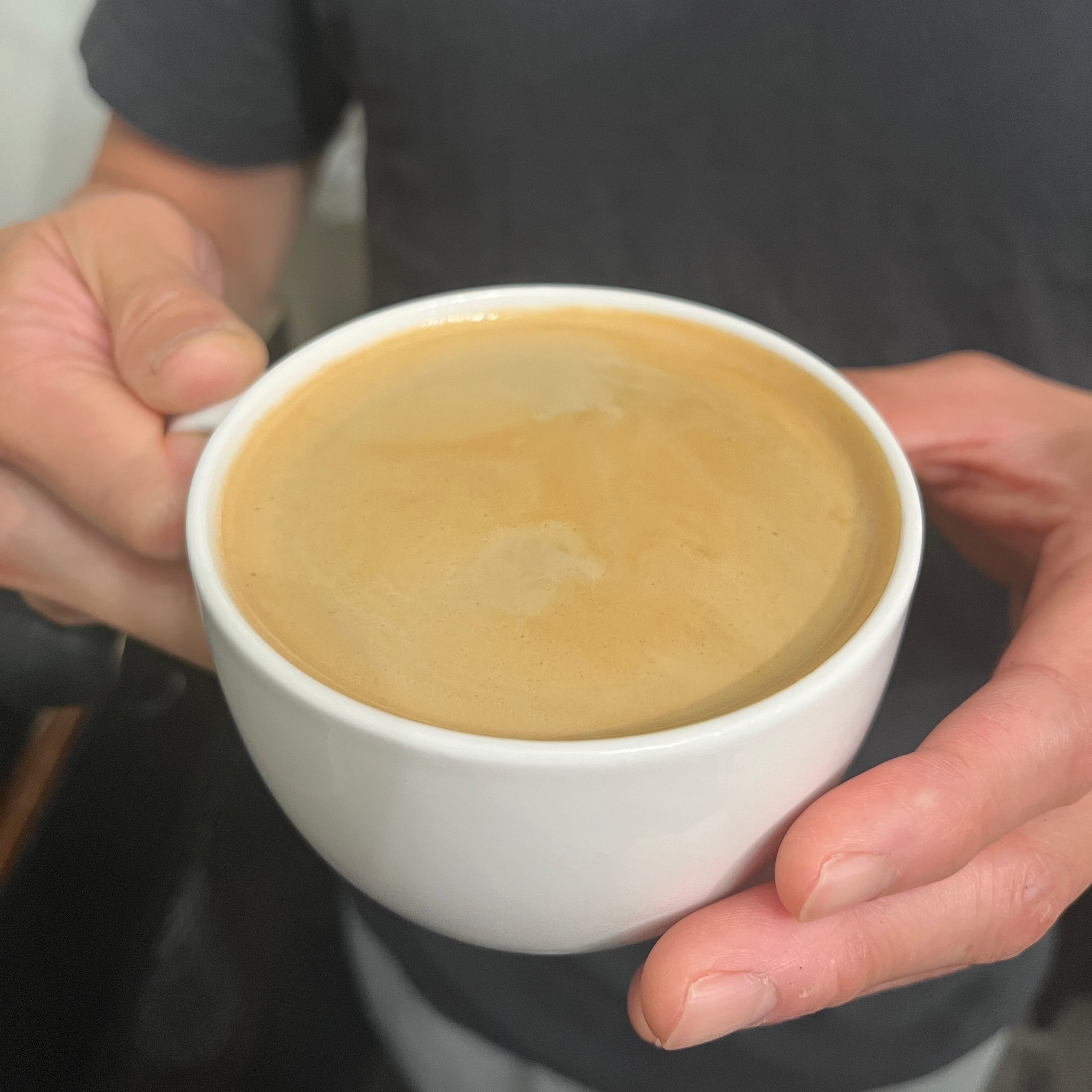 personal holding a white cup with espresso shot in it